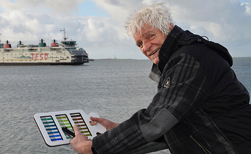Fysisch oceanograaf Dr. Marcel Wernand met de Forel-Ule kleurenschaal op de NIOZ meetsteiger in het Marsdiep