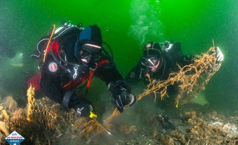 Duikers halen netten van de bodem van de Waddenzee - © Joost van Uffelen